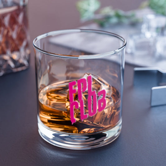 Glass of whiskey with pink text on a dark surface