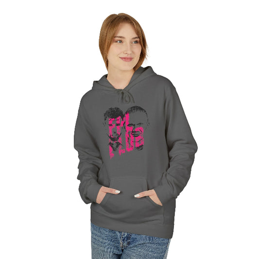 A woman wearing a dark gray pullover hoodie with a pink and black graphic print on the front, paired with blue jeans, set against a plain white background.