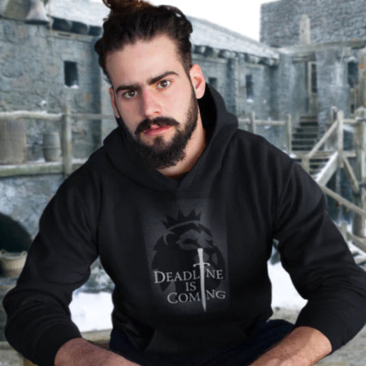 Man wearing a black hoodie with a design and text in front of a stone building.