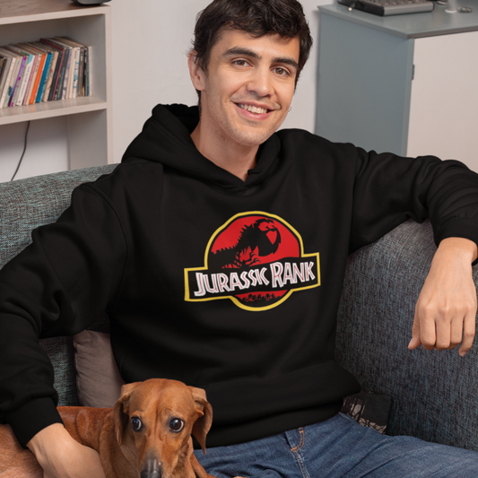 Man wearing a black hoodie with a 'Jurassic Rank' logo, sitting on a couch with a small dog.