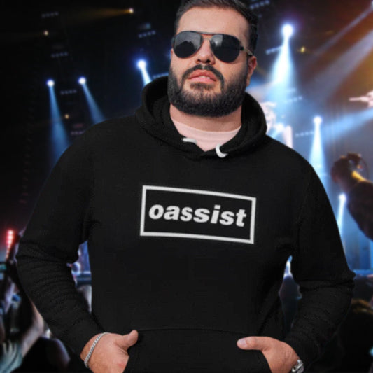 Man wearing a black hoodie with 'oassist' logo in a concert setting