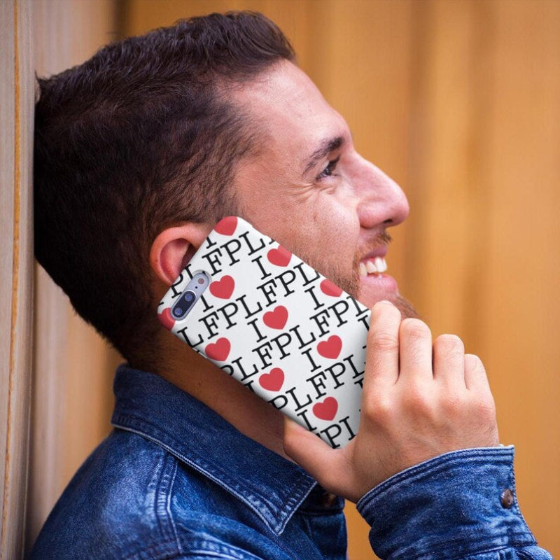 Man holding a phone with a patterned case against a beige wall