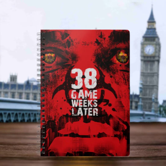 Notebook with a red cover featuring text and a graphic design, set against a blurred background with a clock tower.