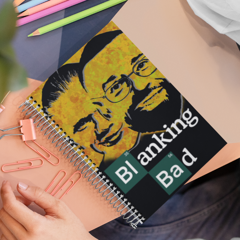 Notebook with a 'Breaking Bad' design held by a person, with colorful pencils in the background.