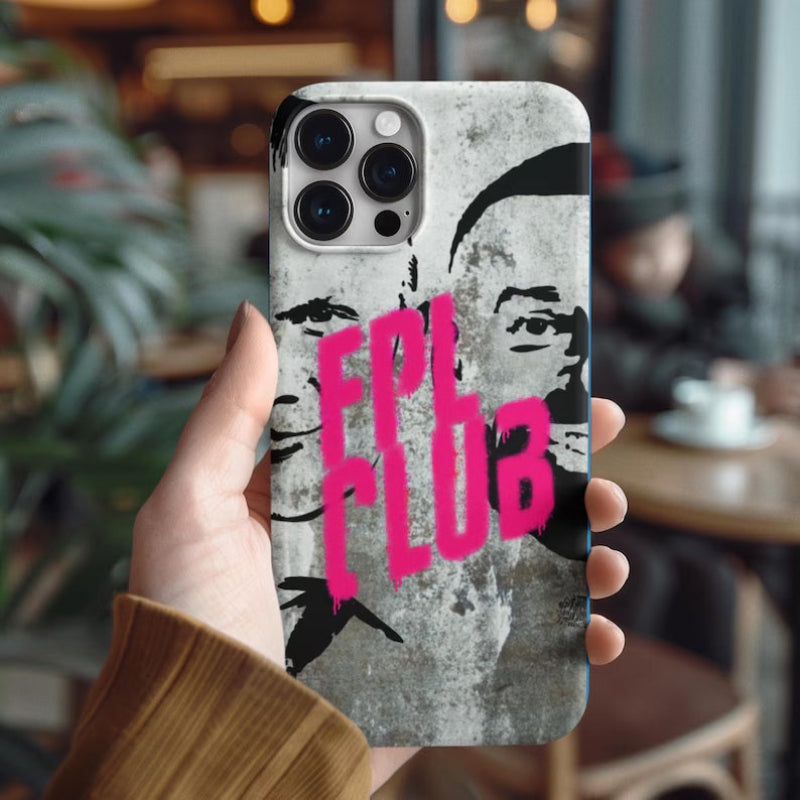 Phone case with pink text held by a person in a blurred cafe setting