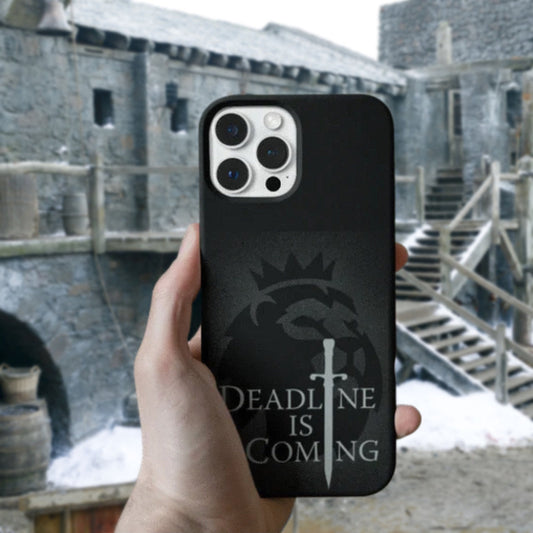 Phone case with 'Deadline is Coming' design held in front of a stone building.