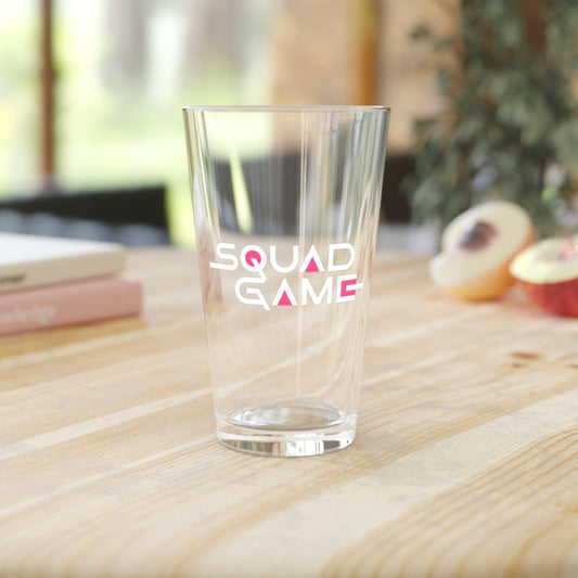 pint glass sitting ontable top with logo 'Squad Game'