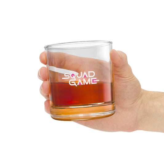 Hand holding a clear glass with red liquid and 'Squad Game' text on a white background
