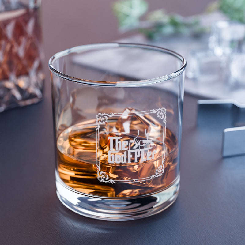 Glass of whiskey with 'The Godfather' branding on a dark surface