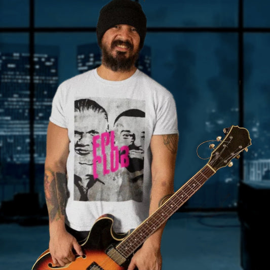 Man holding a guitar wearing a t-shirt with a graphic design in front of a cityscape background