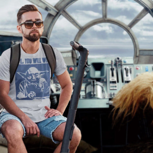 Man wearing a t-shirt with a graphic design, sitting inside a vehicle with a scenic background.