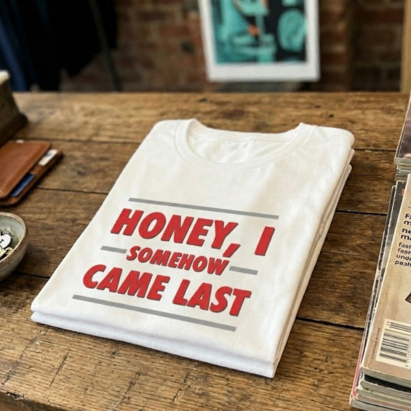 Folded white t-shirt with red text on a wooden table