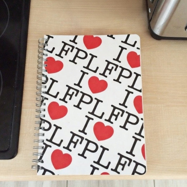 Notebook with red hearts and text on a wooden surface