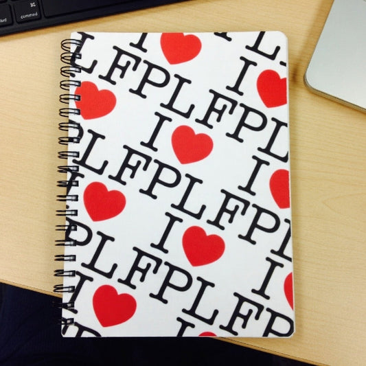 Notebook with 'I ❤️ FPL' text and red hearts on a wooden surface