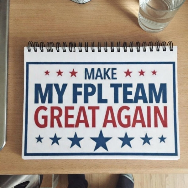 Notebook with 'Make My FPL Team Great Again' text on a wooden table.