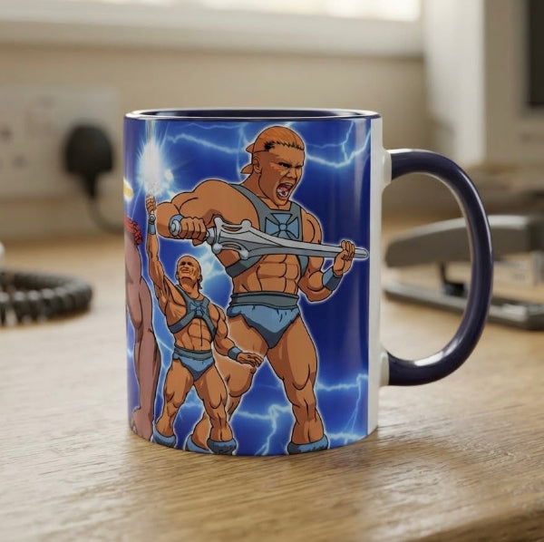 A ceramic mug featuring an illustration of He-Man from He-Man and the Power of Imagination, sitting on a wooden desk with a blurred office background.