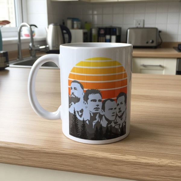 White mug with a graphic design of four men's faces and a sunset on a kitchen counter.