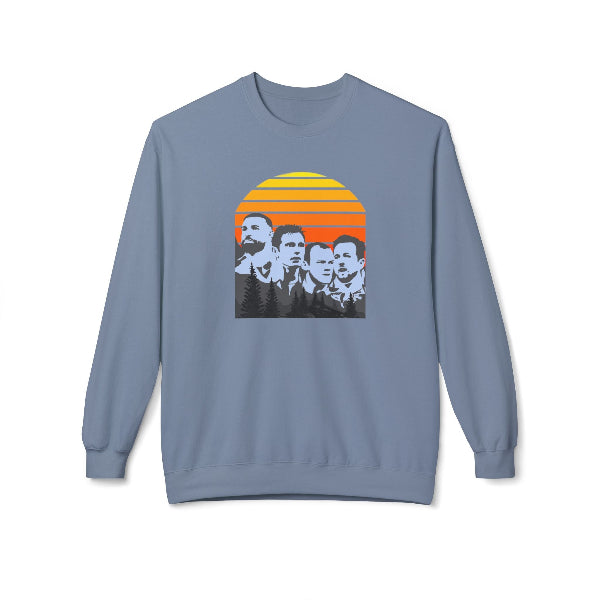 A dusty blue crewneck sweatshirt featuring a graphic print of the four members of the band Nirvana on a retro sunset background, displayed against a plain white background.