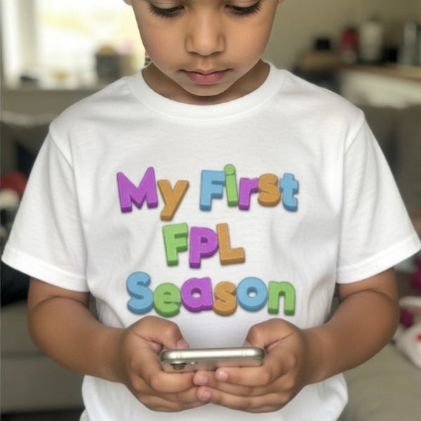Child wearing a white t-shirt with colorful text, holding a phone.