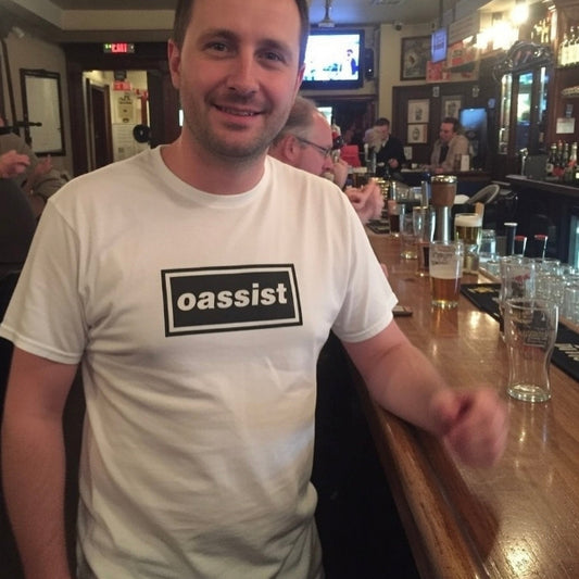 Man wearing a white t-shirt with 'oassist' logo in a bar setting