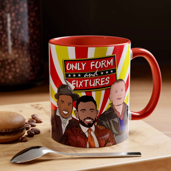 A ceramic mug with a red handle and interior, featuring a red, yellow, and white striped circus-style background and cartoon portraits of three men under the text 'ONLY FORM and FIXTURES.' The mug sits on a wooden surface with a spoon in front and a blurred jar of coffee beans in the background.
