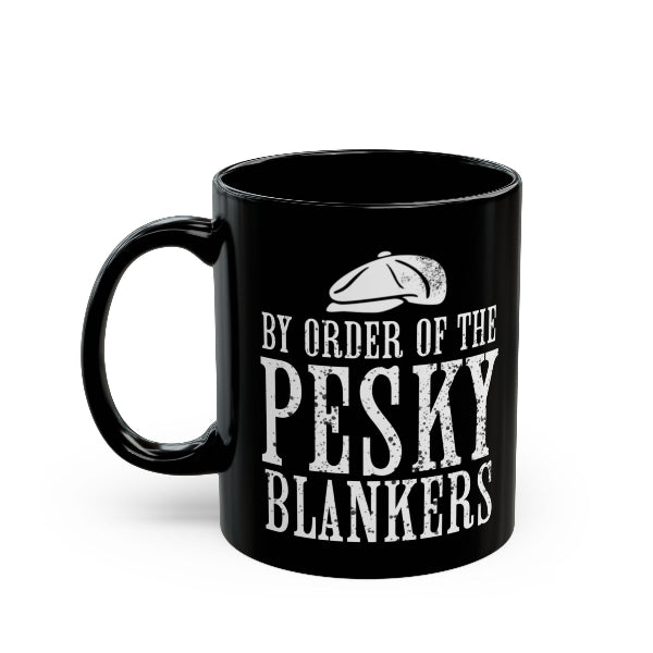 A black ceramic mug with a white distressed typographic design reading 'BY ORDER OF THE PESKY BLANKERS' and a small flat cap graphic above the text, shown on a plain white background.