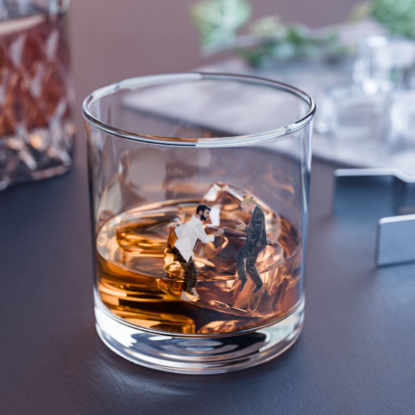Glass with liquid and two small figures on a table