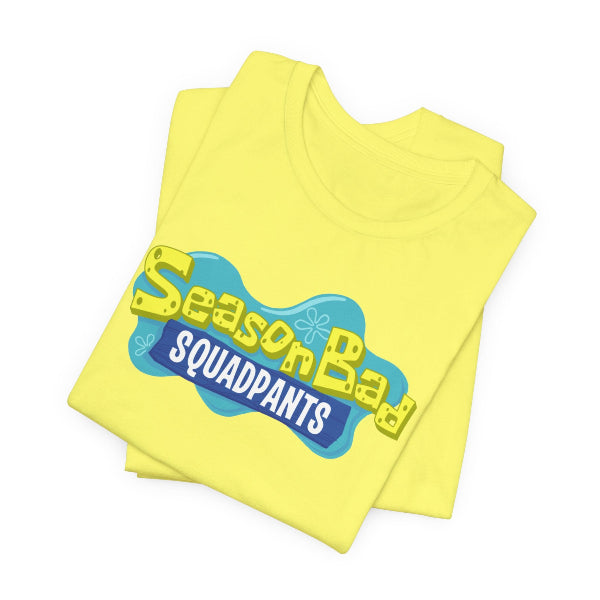 A folded yellow t-shirt featuring a 'Season Bad Squaddpants' graphic on the front, set against a plain white background.