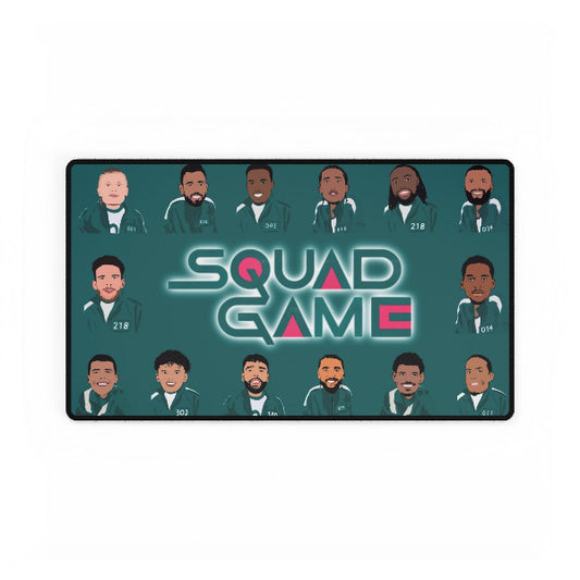 A rectangular desk mat featuring an illustration of characters from the TV show 'Squid Game' on a dark teal background. The mat includes 16 stylized character portraits arranged around the central title 'SQUAD GAME' in a glowing font.