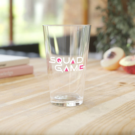 Clear glass with 'SQUAD GAME' text on a wooden surface
