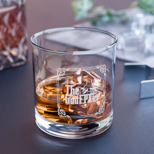 Glass of whiskey with an engraved design on a dark surface