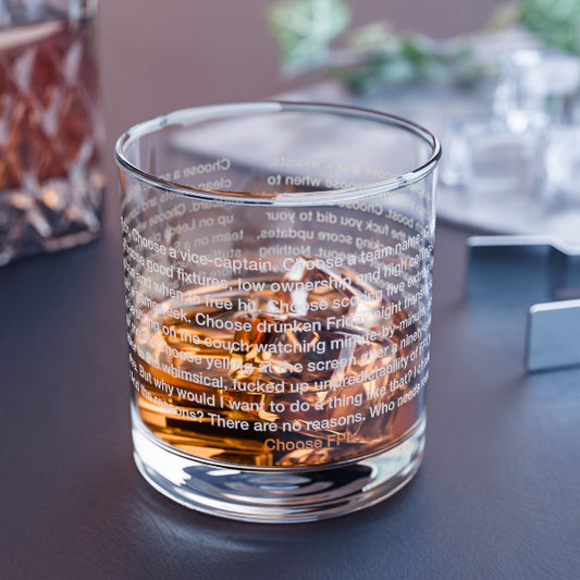 Glass tumbler with text and whiskey on a dark surface